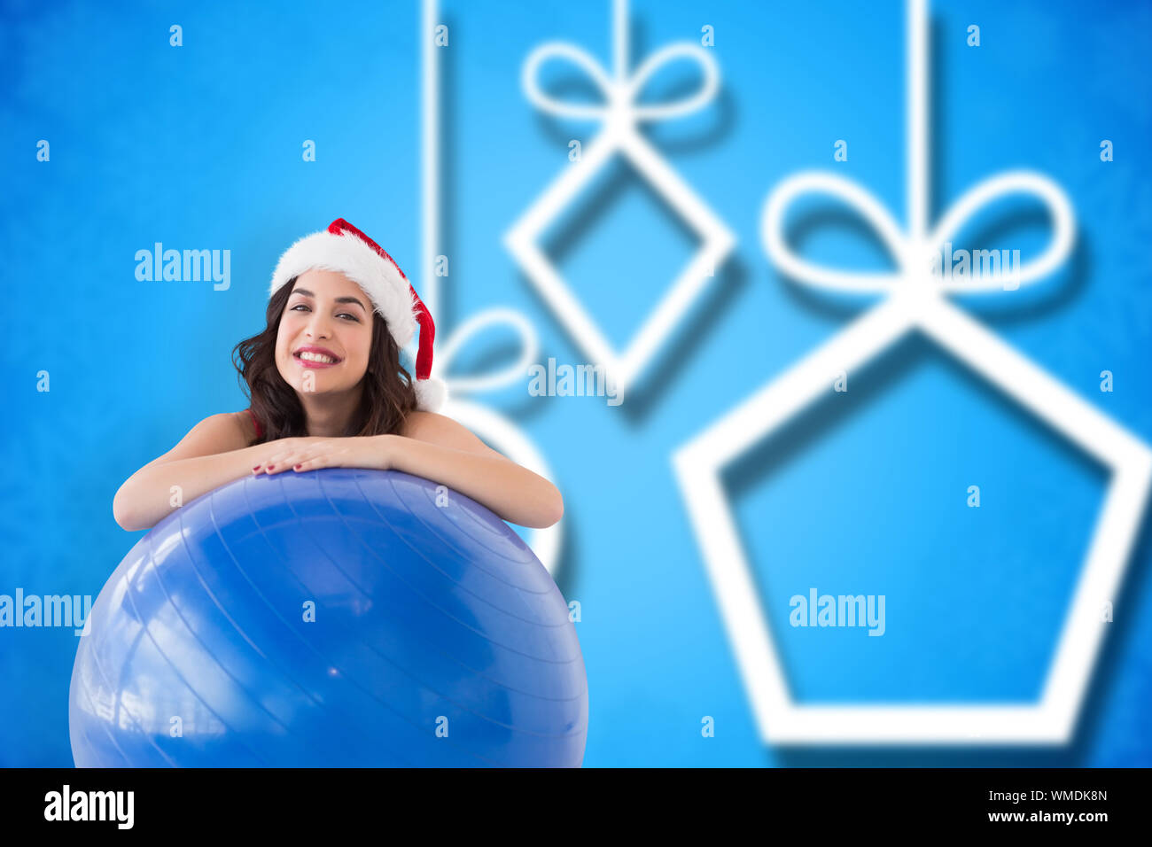 Festive fit brunette leaning on exercise ball  against blurred christmas background Stock Photo