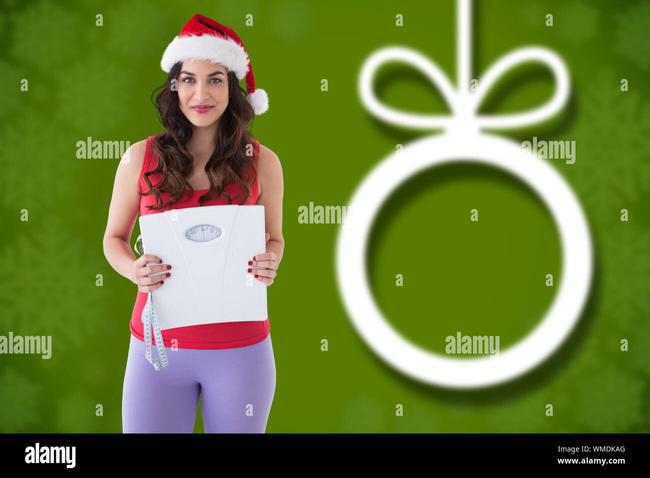 Festive fit brunette holding page and measuring tape against blurred christmas background Stock Photo