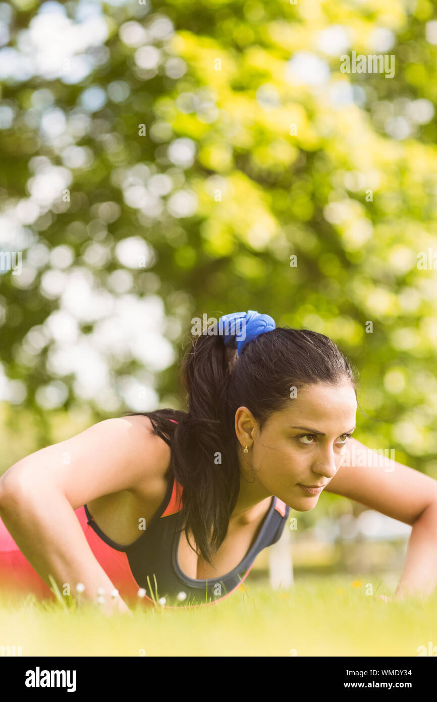 Fit determined brunette doing push ups in the park Stock Photo