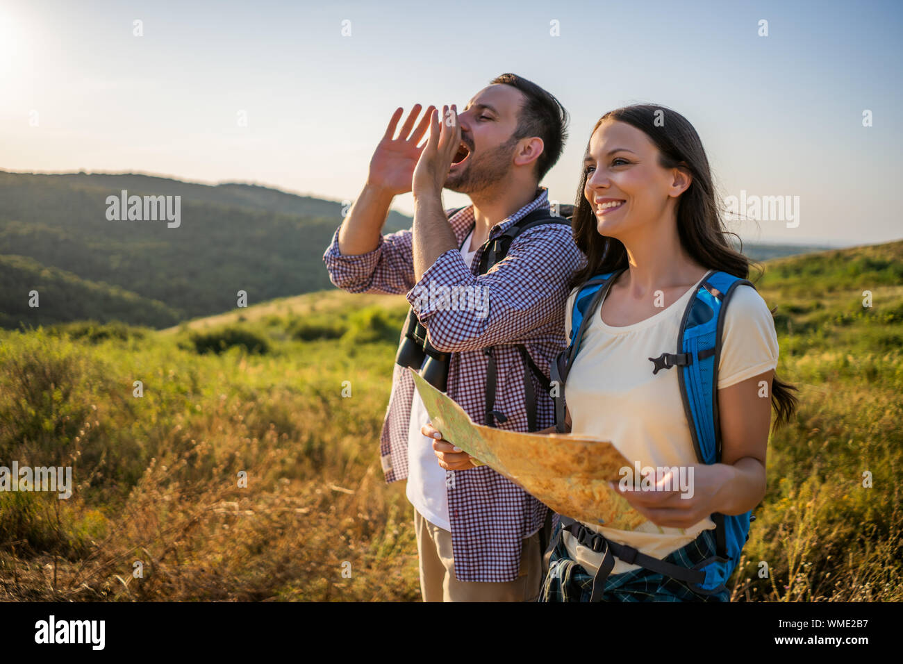 Happy couple is hiking in mountain. They are looking at map Stock Photo ...