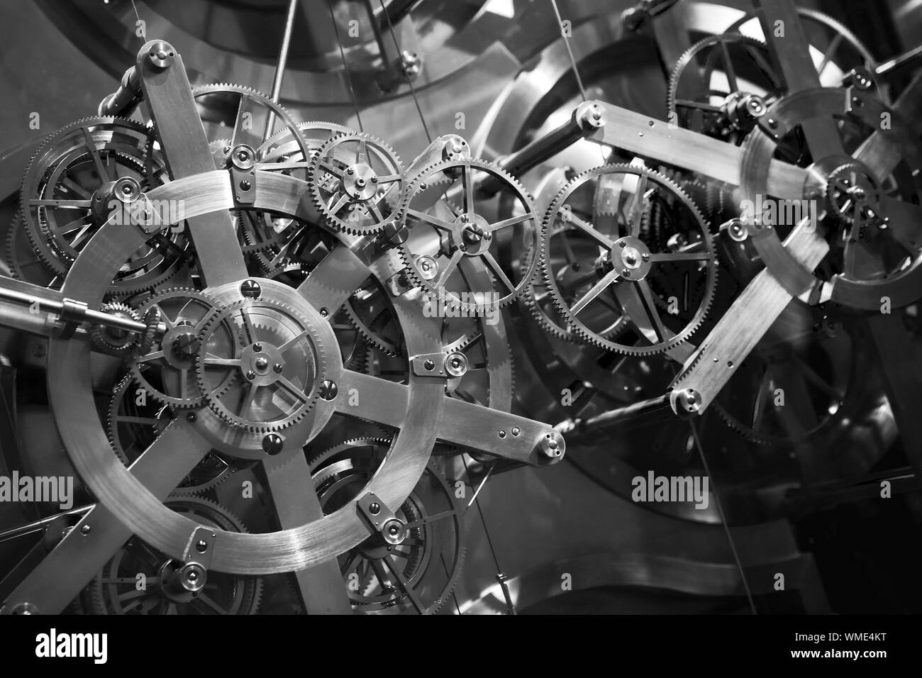 Vintage world clock mechanism, fragment with shiny cog wheels. Black