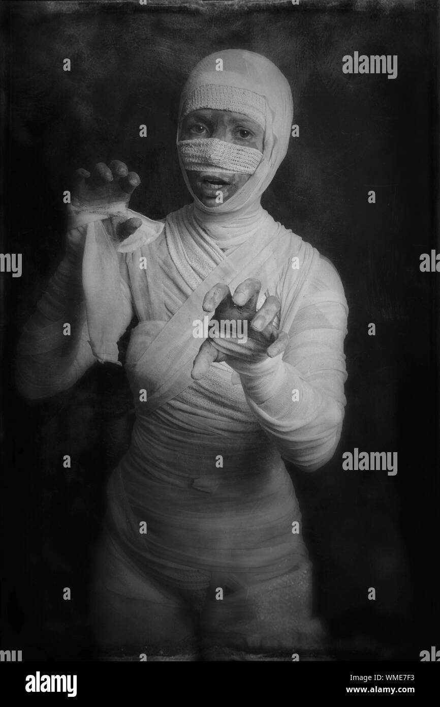 Portrait Of Woman Wearing Mummy Costume Standing By Wall During Halloween Stock Photo