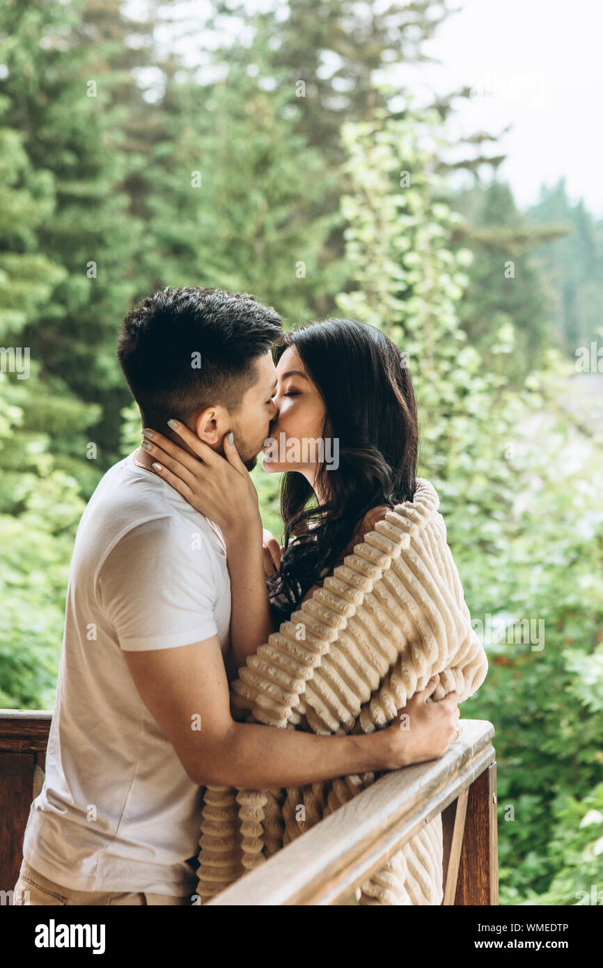 A man hugs and kisses a woman on the balcony. They have a honeymoon or  close relationship and love Stock Photo - Alamy