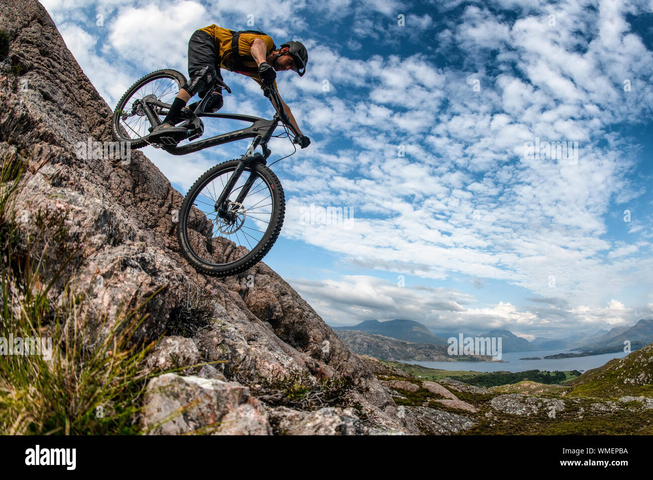 A man rides a mountain bike down a rock slab on the Applecross peninsula in the north west Highlands of Scotland. Stock Photo