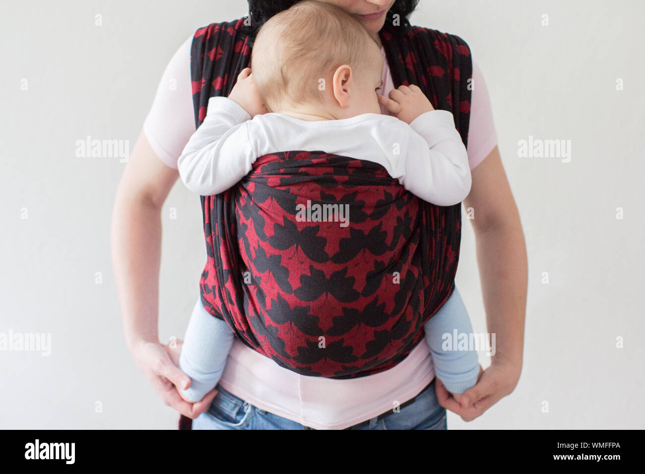 Midsection Of Woman Carrying Baby In Harness Stock Photo