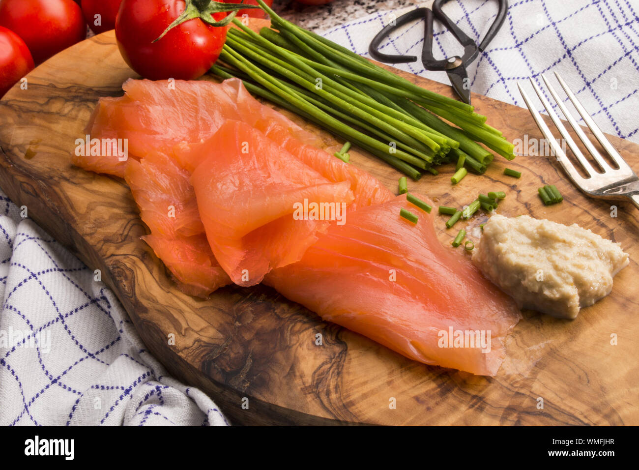 scottish smoked salmon on a wooden board with chive, tomato, horseradish and fork Stock Photo