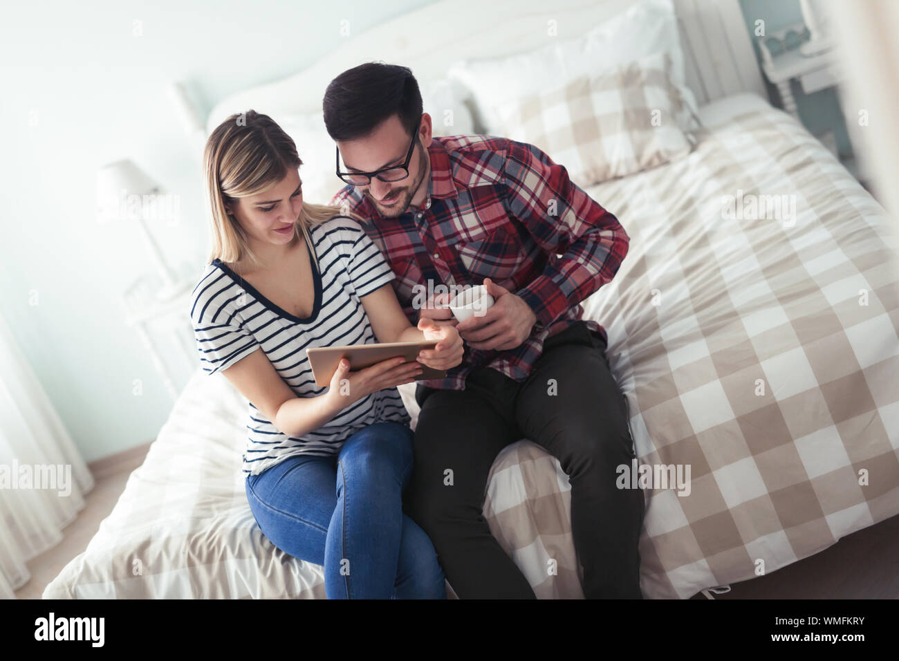 Happy couple using digital tablet in bedroom Stock Photo