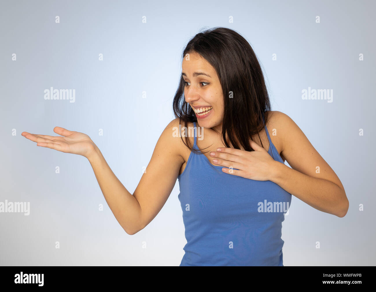 Portrait of happy young woman showing empty copy space on open hand palm looking excited and surprised. Cheerful teenager girl presenting and showing Stock Photo