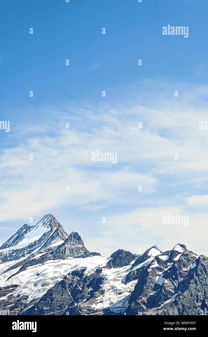 Alpine mountain peaks with blue sky and light clouds. Mountain climbing, mountains. Copy space, a place for text. Motivational background. Hard work. Personal development. Explore concept. Stock Photo