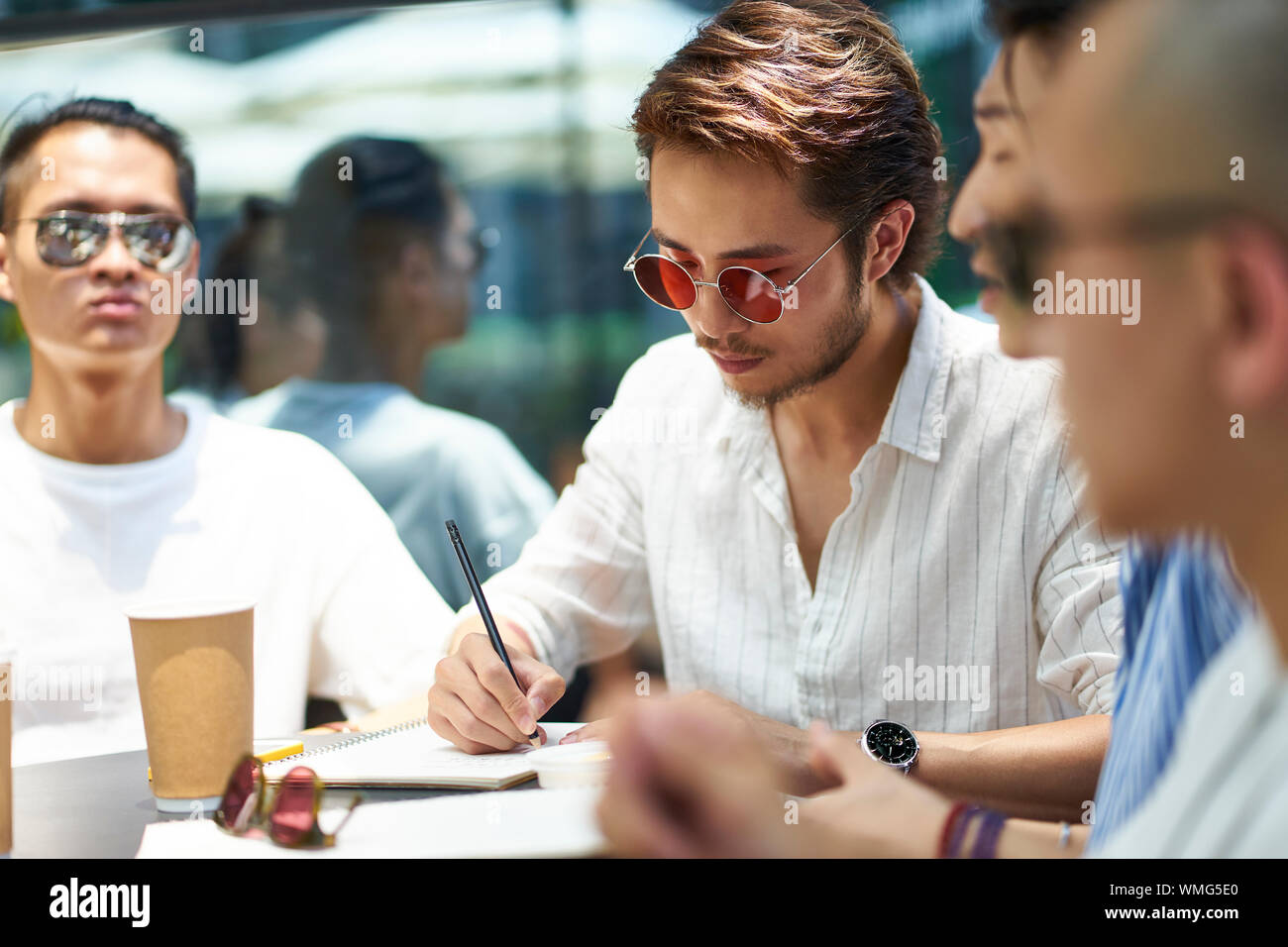 group of young asian university students studying together in an outdoor coffee shop Stock Photo