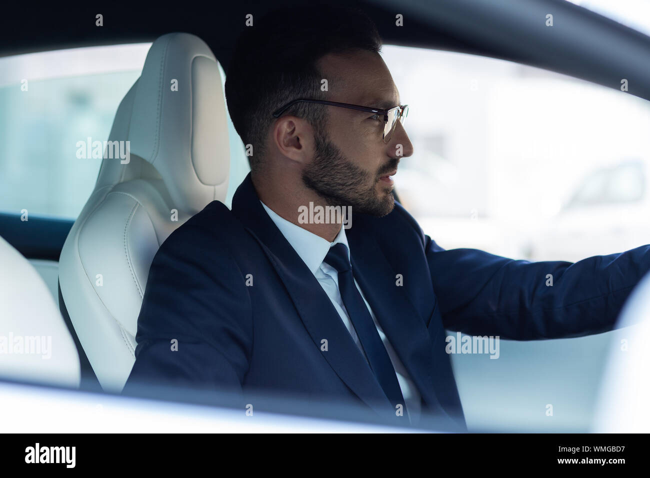 Prosperous businessman feeling thoughtful while driving car Stock Photo
