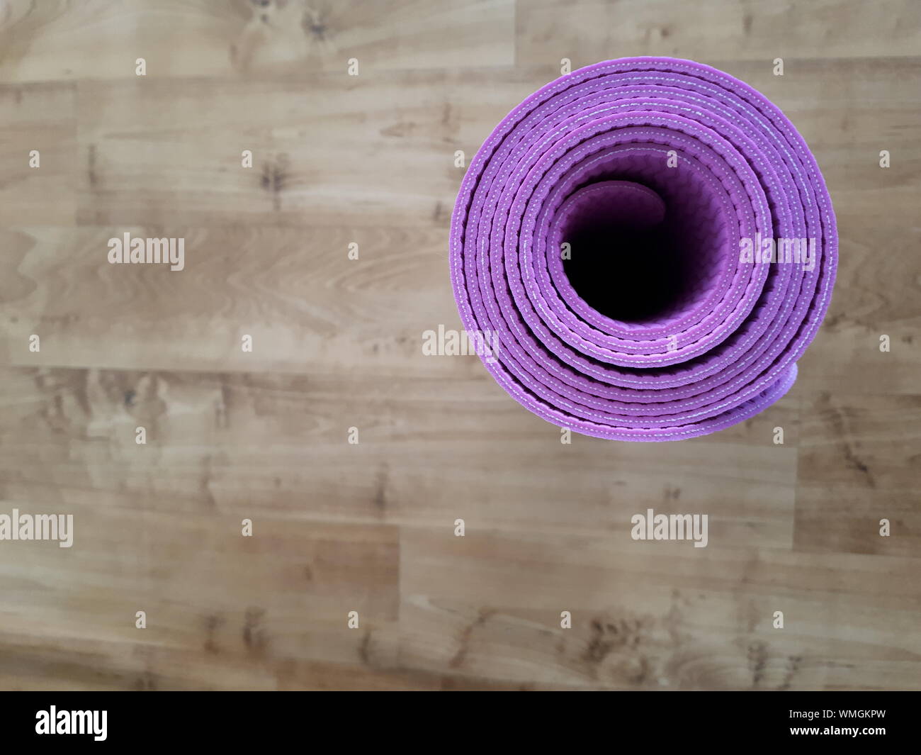 Directly Above Shot Of Purple Exercise Mat Rolled On Hardwood