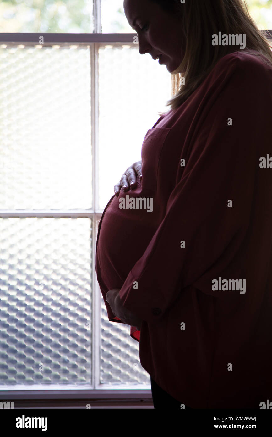 Silhouette of a prgnant woman standing infront of a window Stock Photo ...