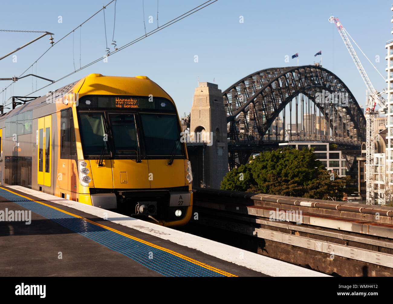 Sydney Harbour Bridge with Train approaching Milsons Point Railway Station. Sunny morning. Blue Sky. Stock Photo
