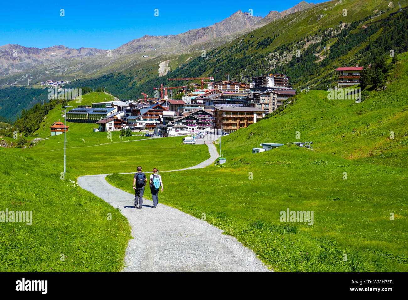 Two hikers with green mountains and blue sunny day at Obergurgl, Ötztal Valley, Austria, Stock Photo