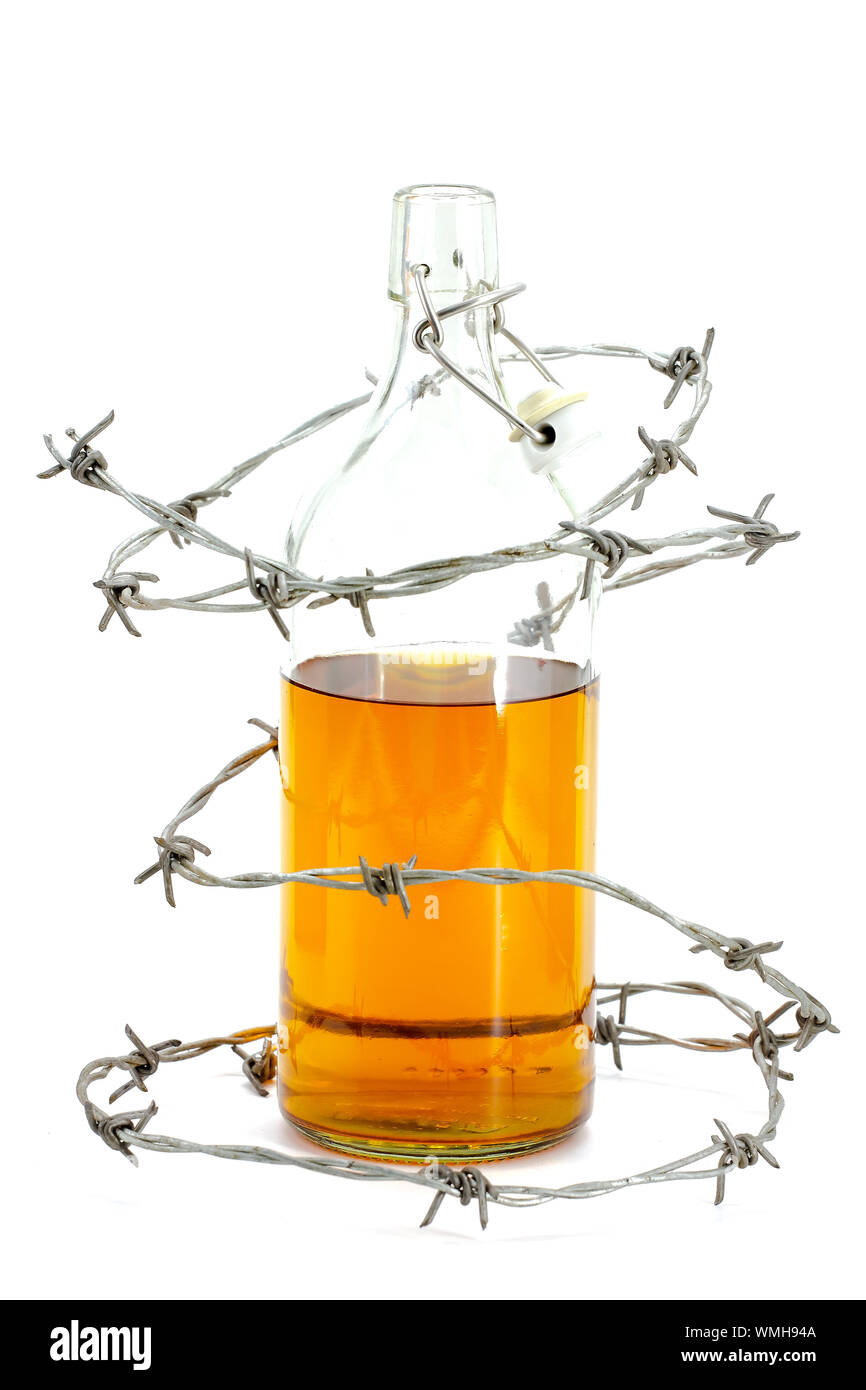 Barbed wire around a glass bottle of alcohol on a white background Stock Photo