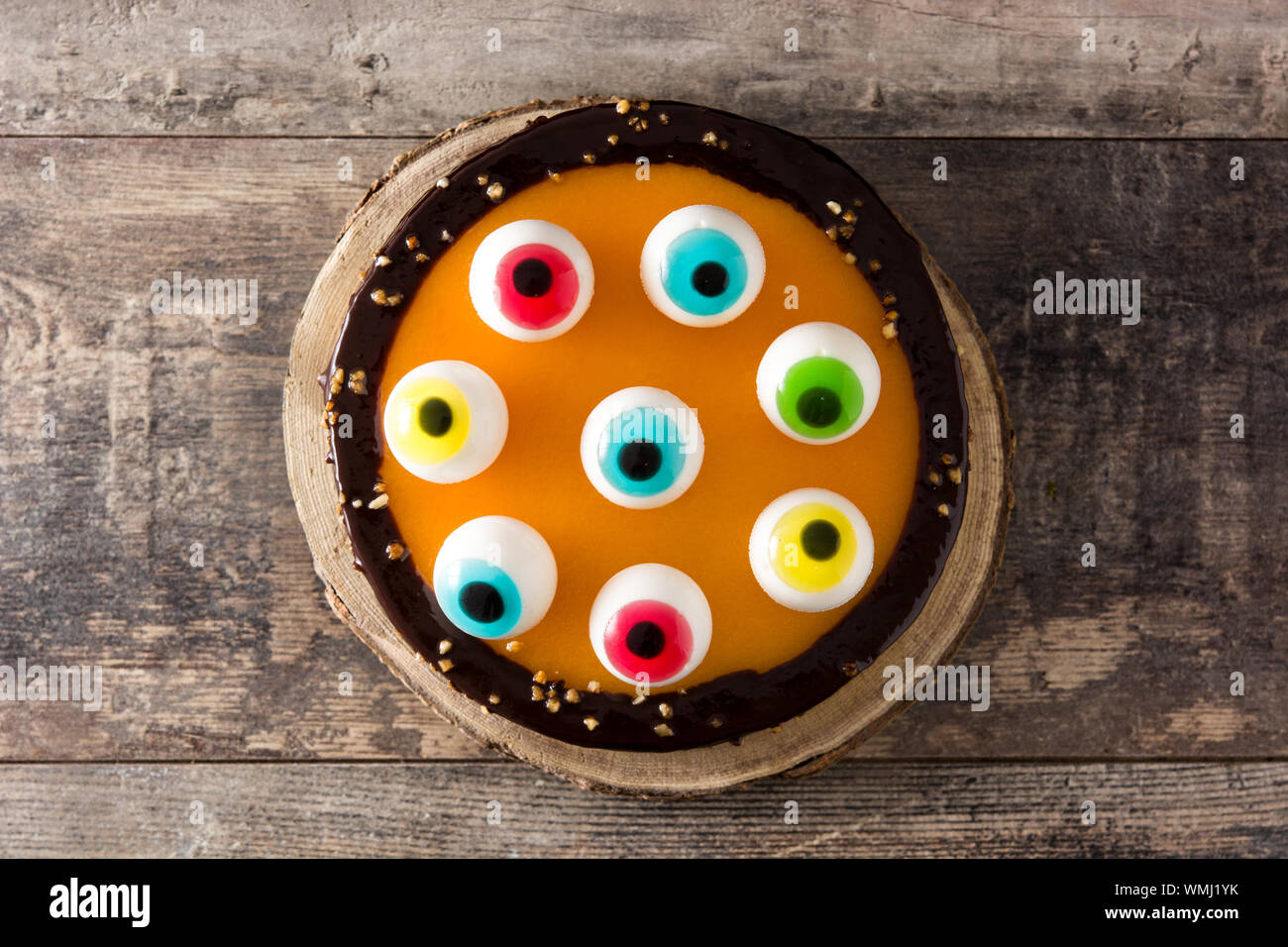 Halloween cake with candy eyes decoration on wooden table. Top view