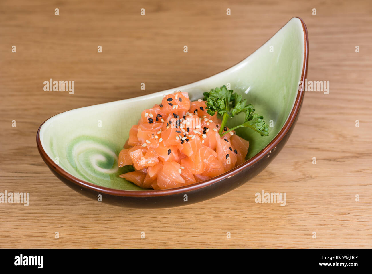 fresh salmon tartare with black and white sesame, served on a boat-shaped plate Stock Photo