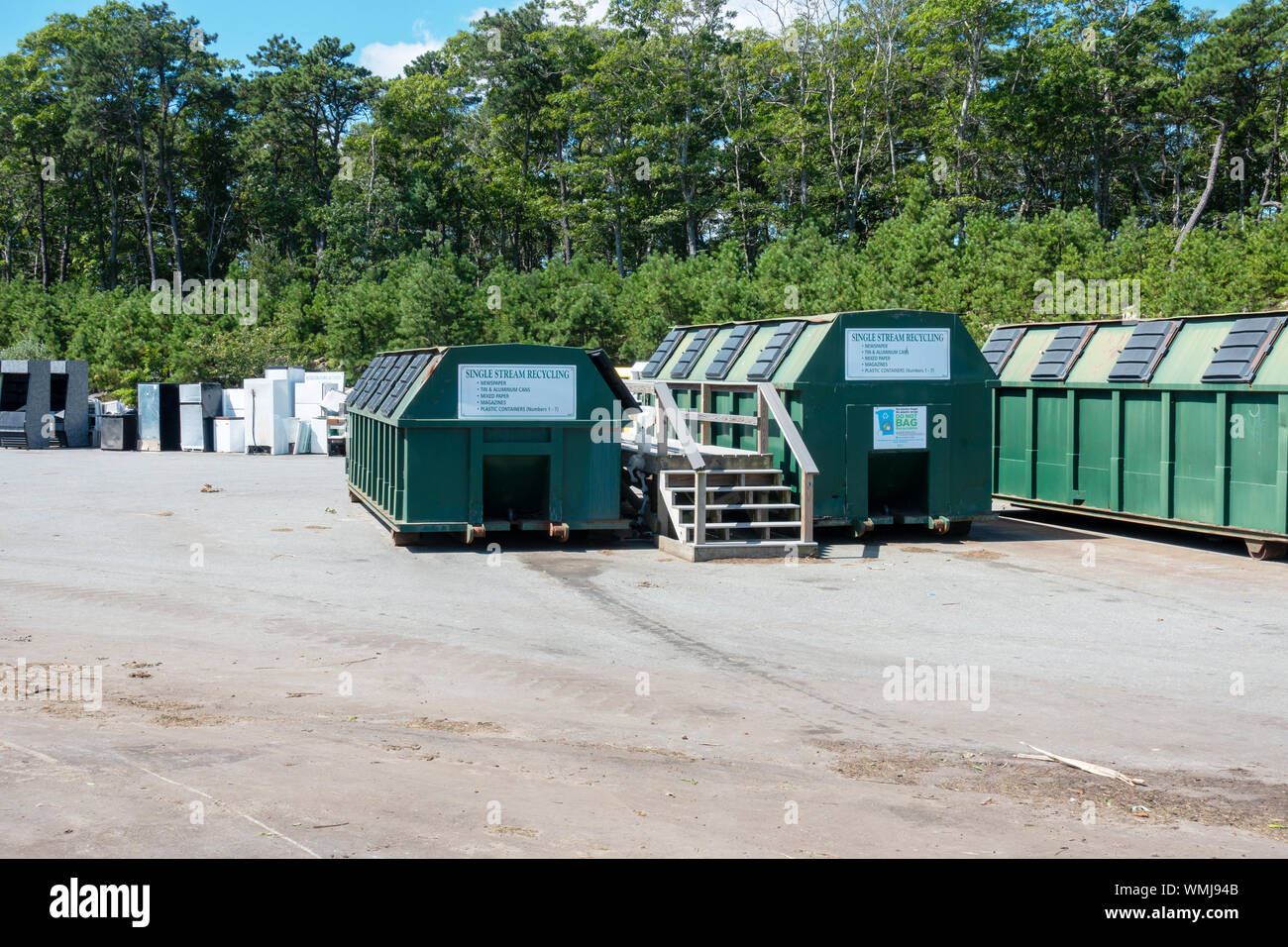 Single stream recycling containers at landfill with appliances incl. refridgerators beyond Stock Photo