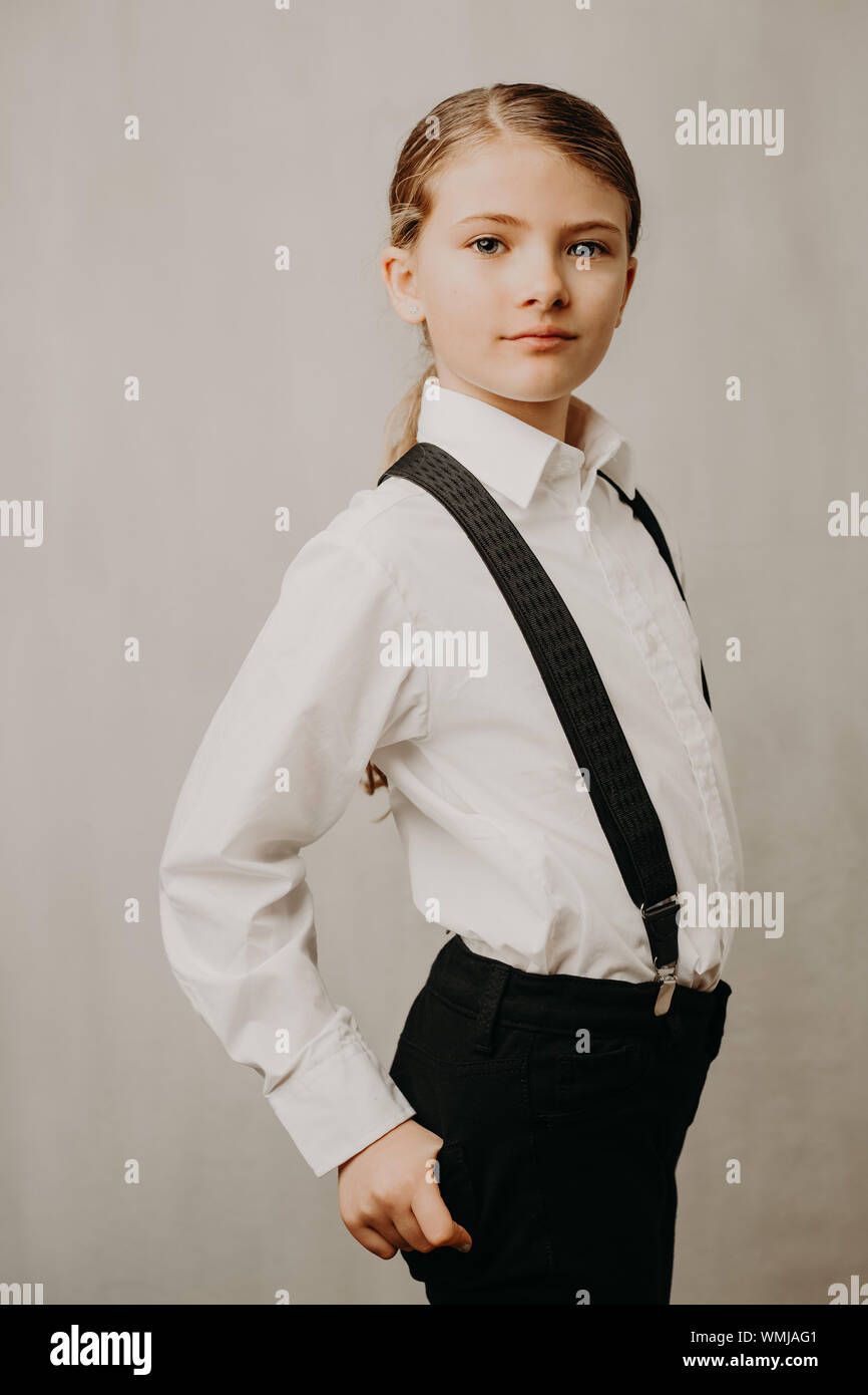 Portrait Of Girl Wearing Suspenders And Shirt Against White Background Stock Photo