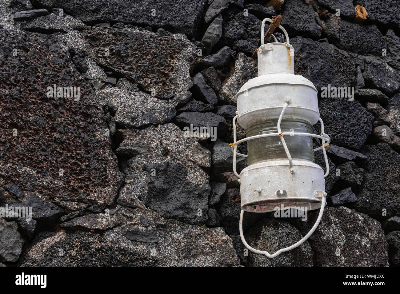 Antique white metal lamp, hanging on a stone wall Stock Photo