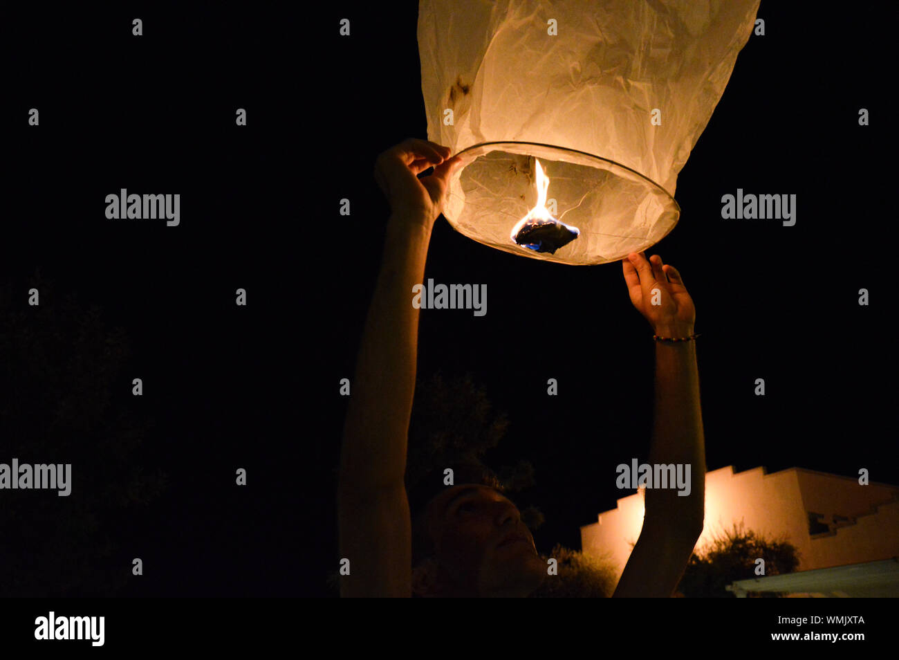 Man Releasing Paper Lantern At Night Stock Photo