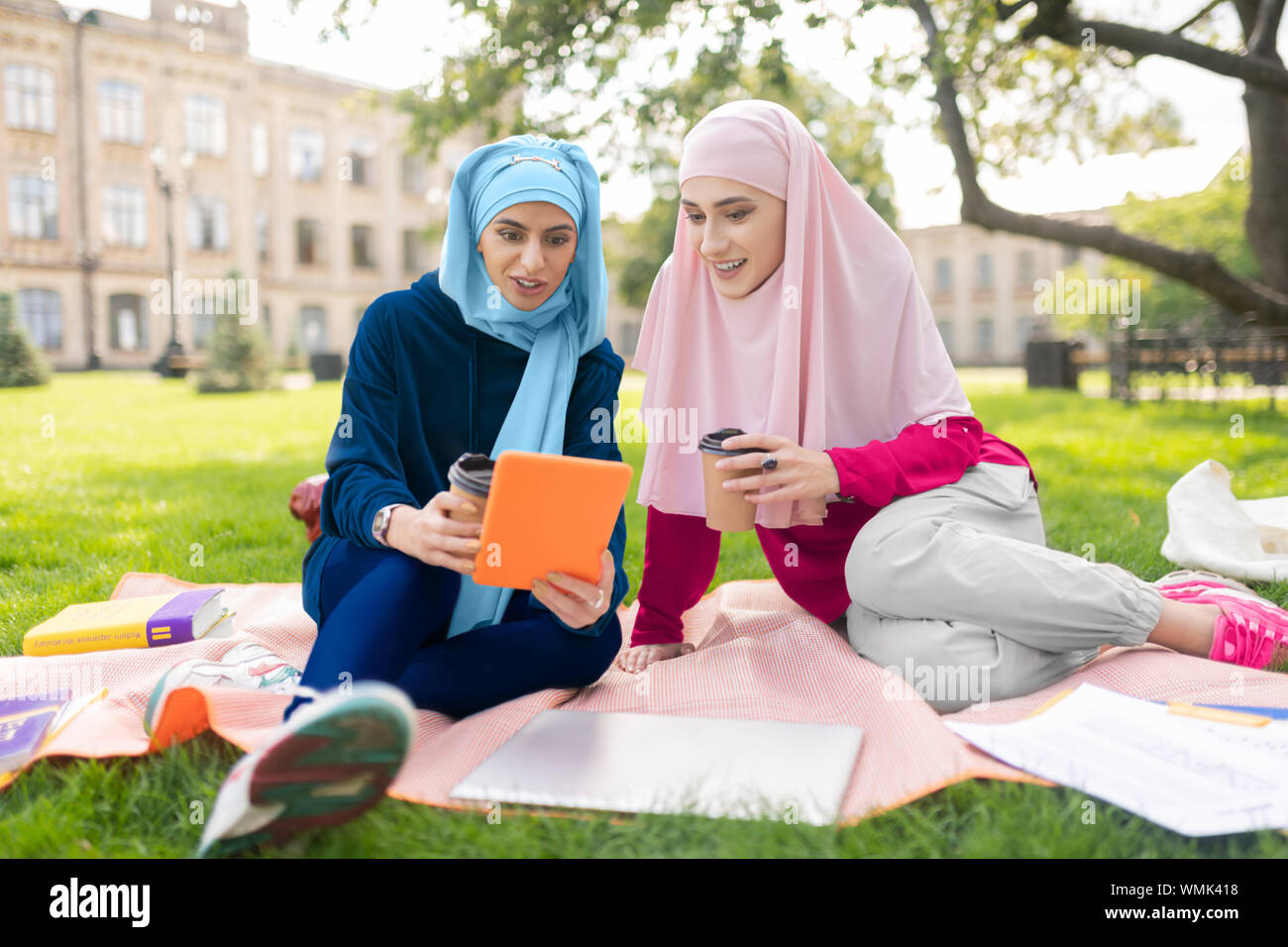 Muslim students watching video on tablet and drinking coffee Stock Photo