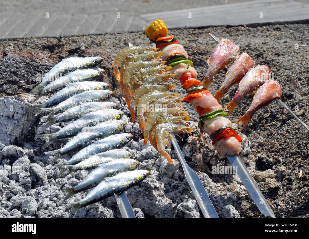 Sardines and other fish being cooked on hot embers at popular seafood