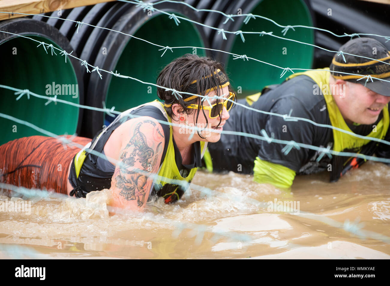 Competitors negotiate the ‘Kiss of Mud’ obstacle at the Tough Mudder endurance event in Badminton Park, Gloucestershire UK Stock Photo