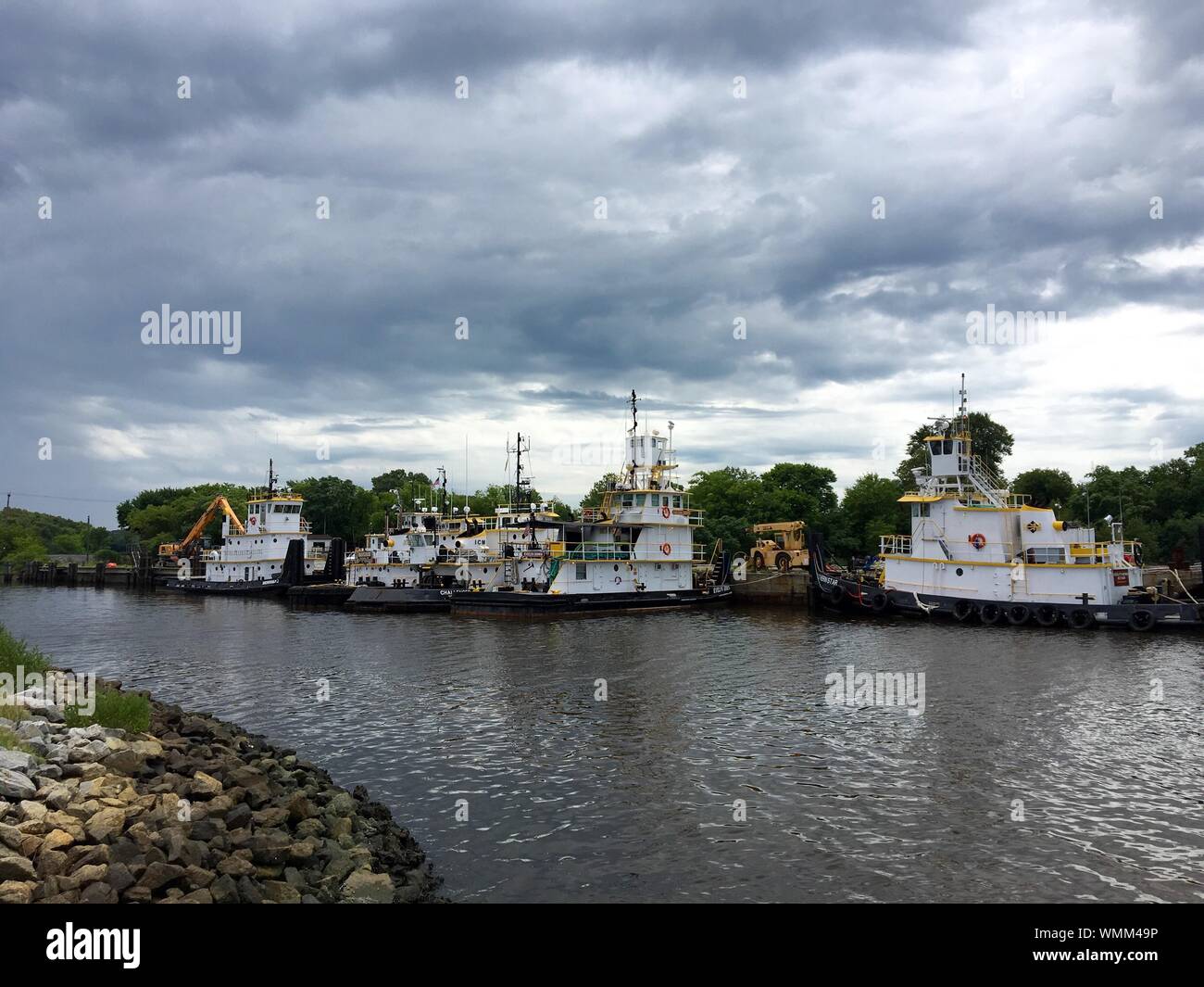 Fishing Boats Moored In Southern Branch Elizabeth River Against Cloudy Sky Stock Photo