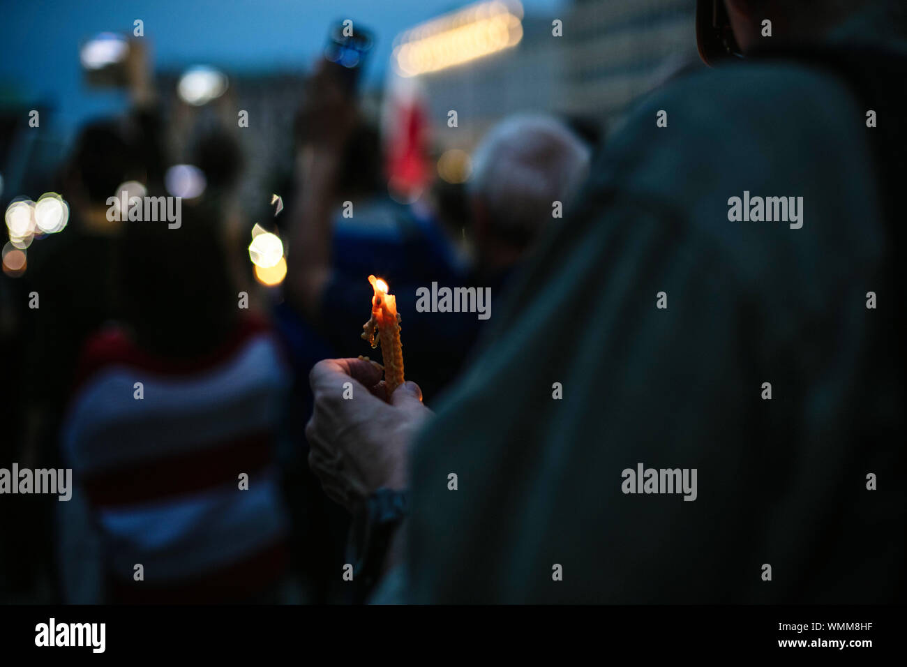 Midsection Of Protestor Holding Burning Candle During Protest At Night Stock Photo
