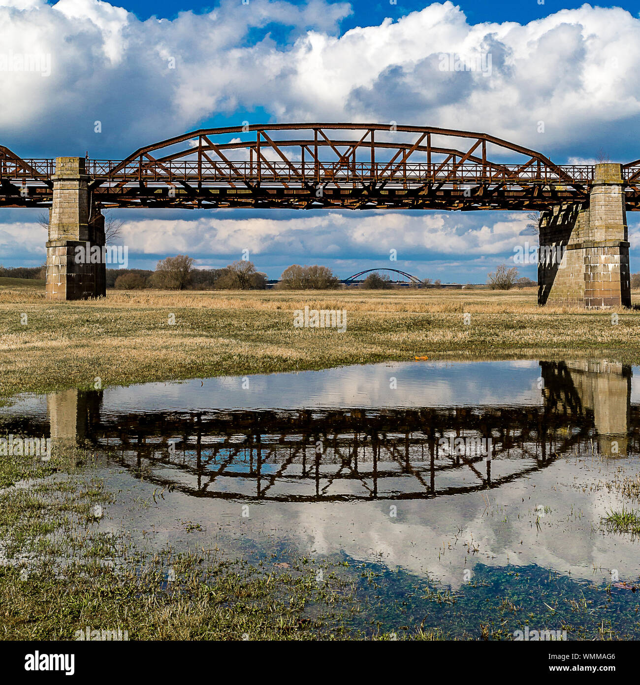 Reflection Of Railway Bridge On Puddle Against Sky Stock Photo