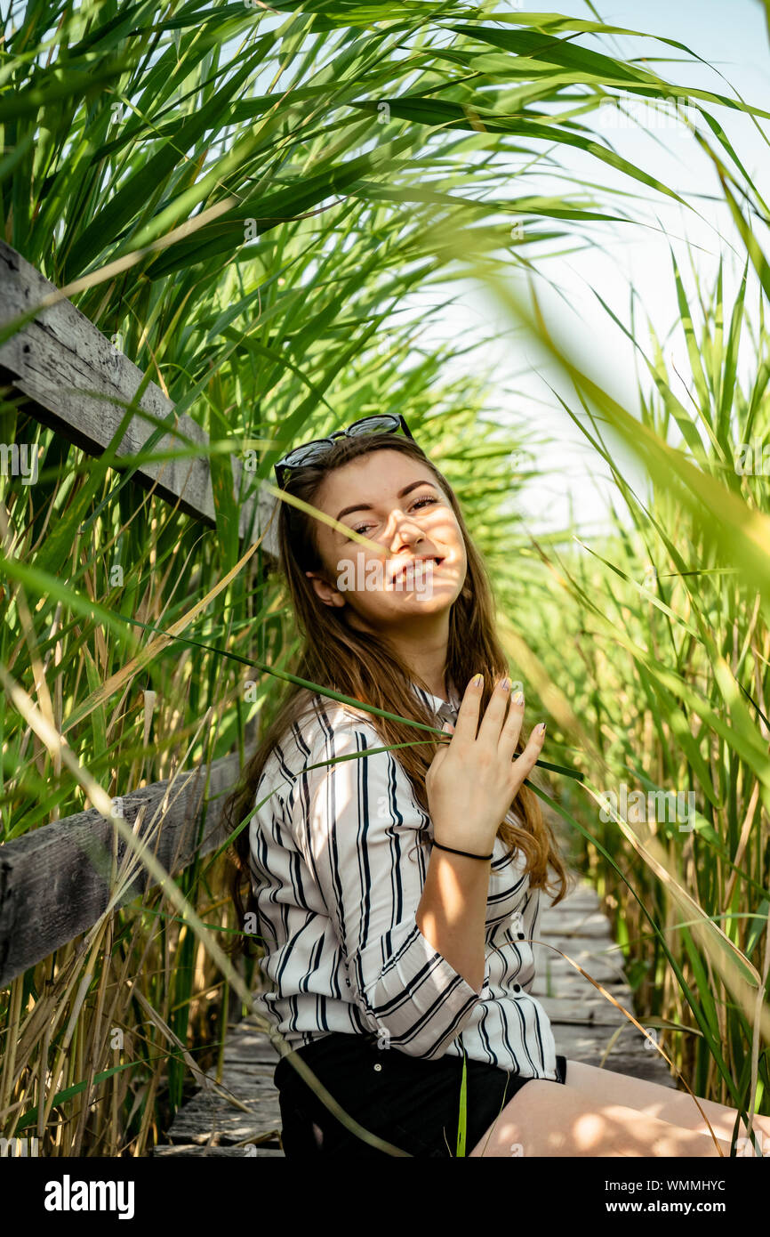 Beautiful Girl Wearing A Striped Shirt Sitting Down On A Wood Path Smiling And Having A Good 