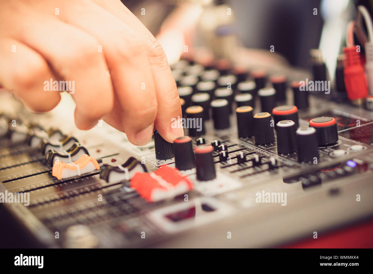 The hand over adjusting knobs on a professional audio mixer for sound