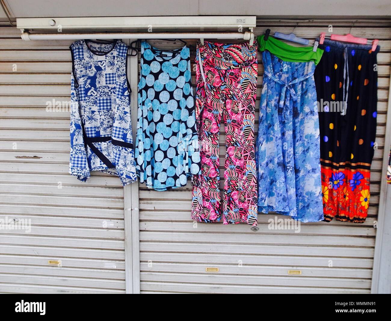 Colorful Womenswear Hanging On Closed Shutter Stock Photo