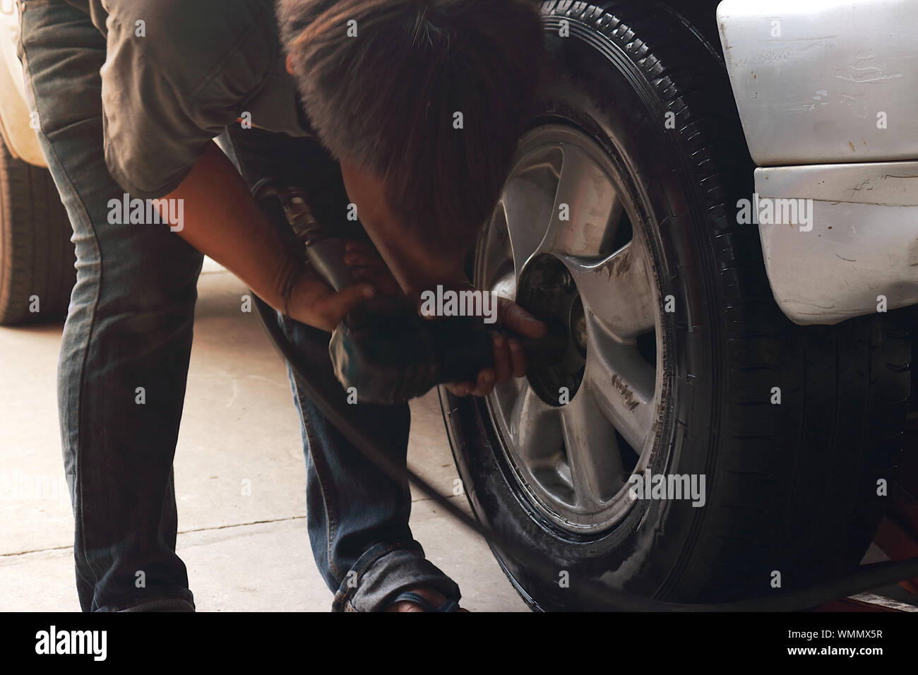 The mechanic is using an air wrench to remove or insert female bolts