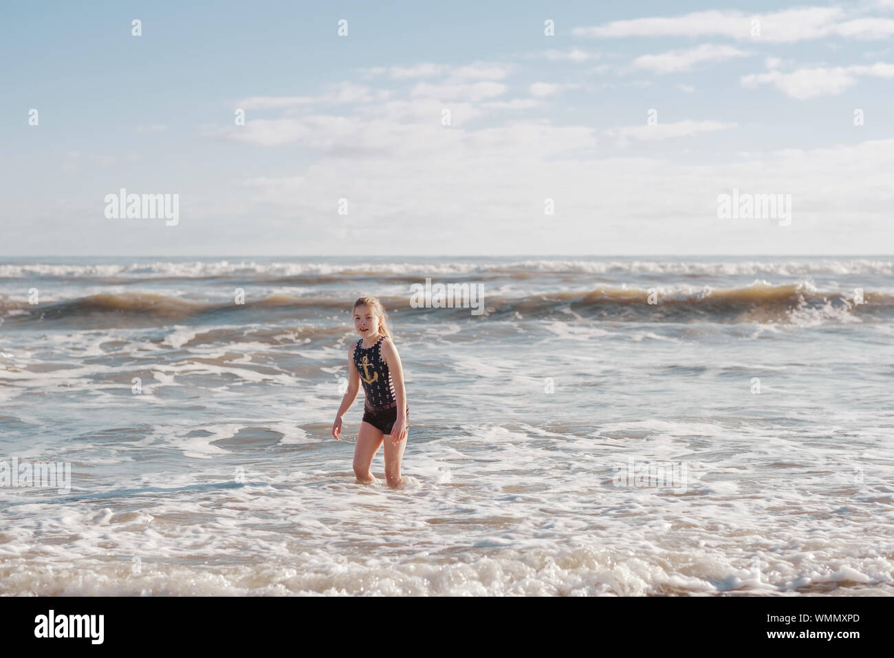 Girl in a swimsuit playing in the surf at the beach Stock Photo