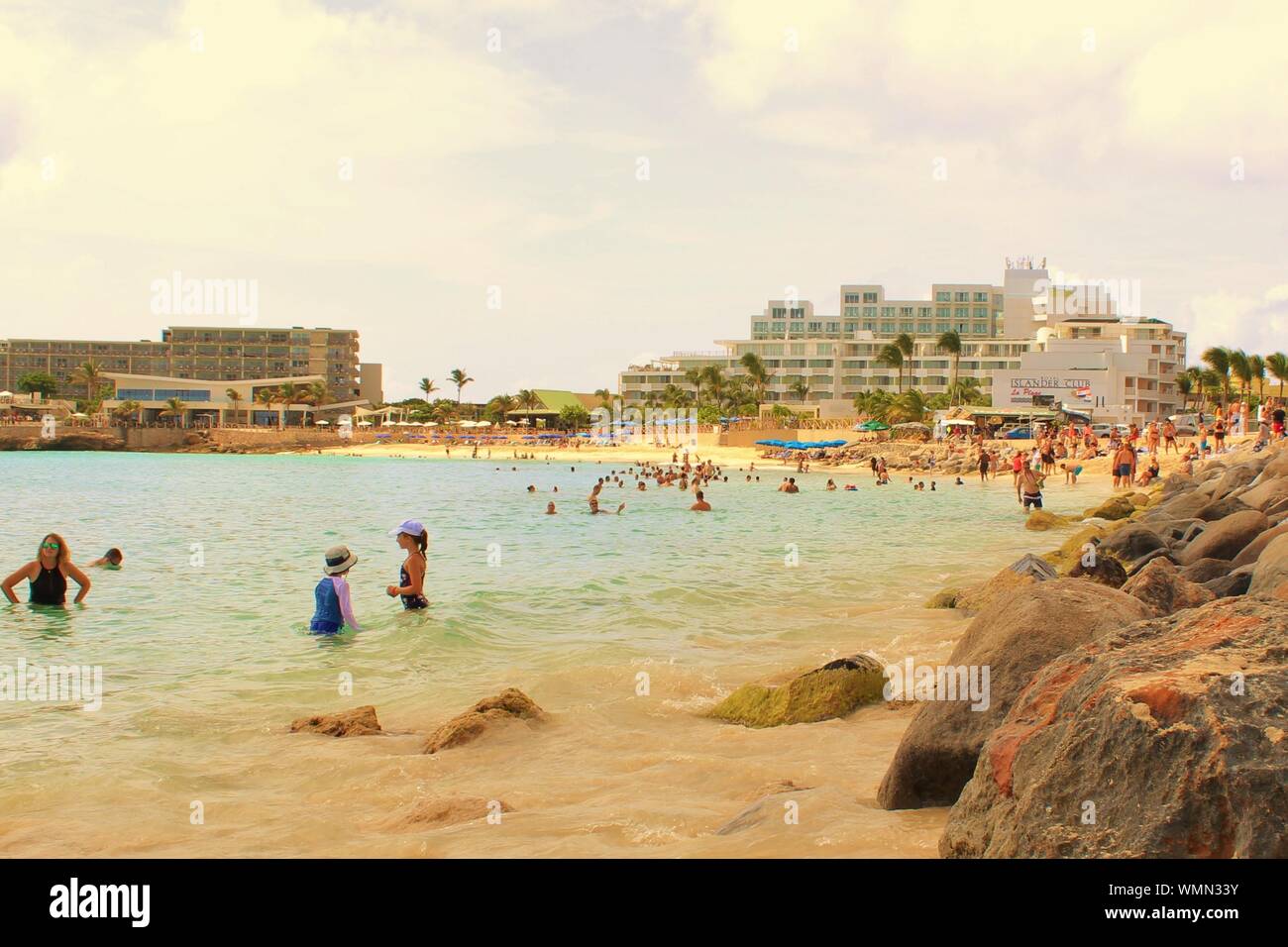 Maho Beach, Sint Maarten - August 19th 2019: Tourists and holidaymakers relax in the sea and on the sands, at Maho beach, St Maarten. Stock Photo