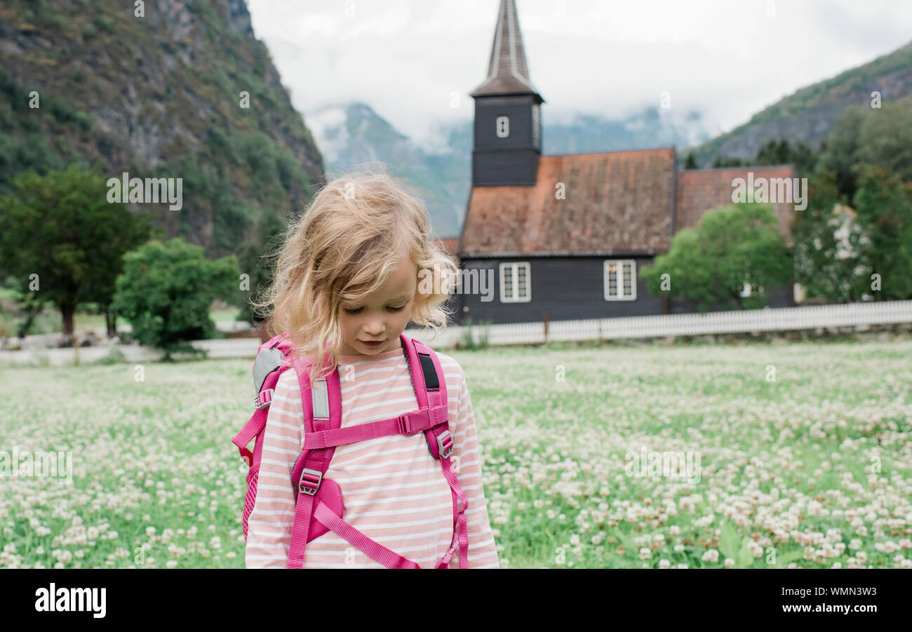 girl backpacking outside a beautiful church & fjord in FlÃ¤m, Norway Stock Photo