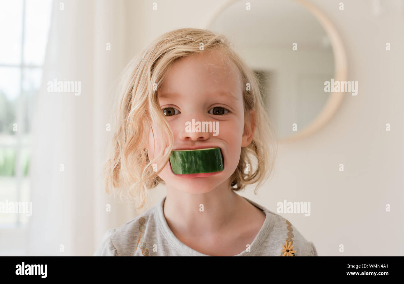 portrait of a young blonde girl with cucumber in her mouth Stock Photo