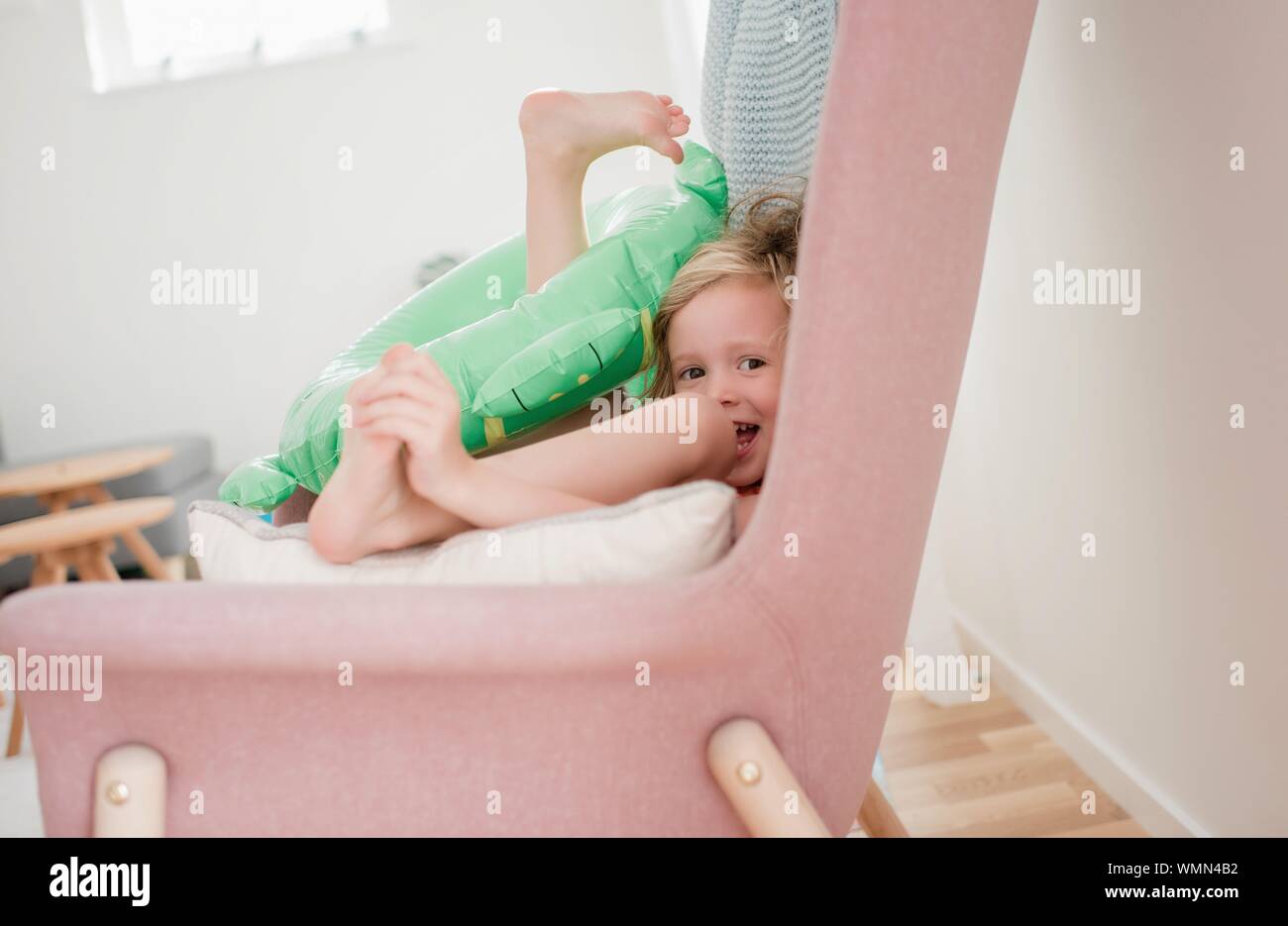 young girl sitting in a chair at home laughing playing with toys Stock Photo