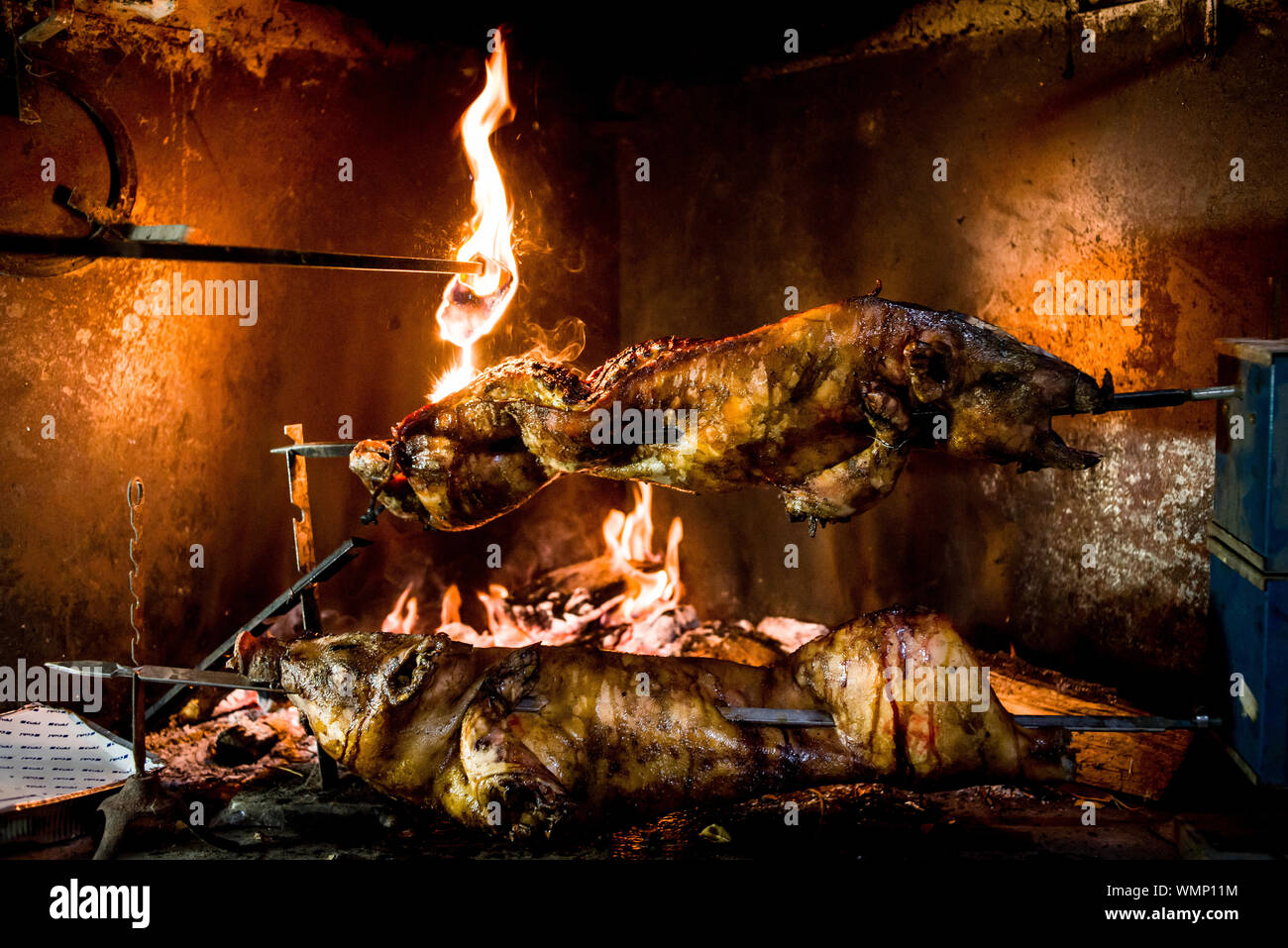 Grilled pigs on spit above the grill at the fireplace in Sardinia, Italy Stock Photo