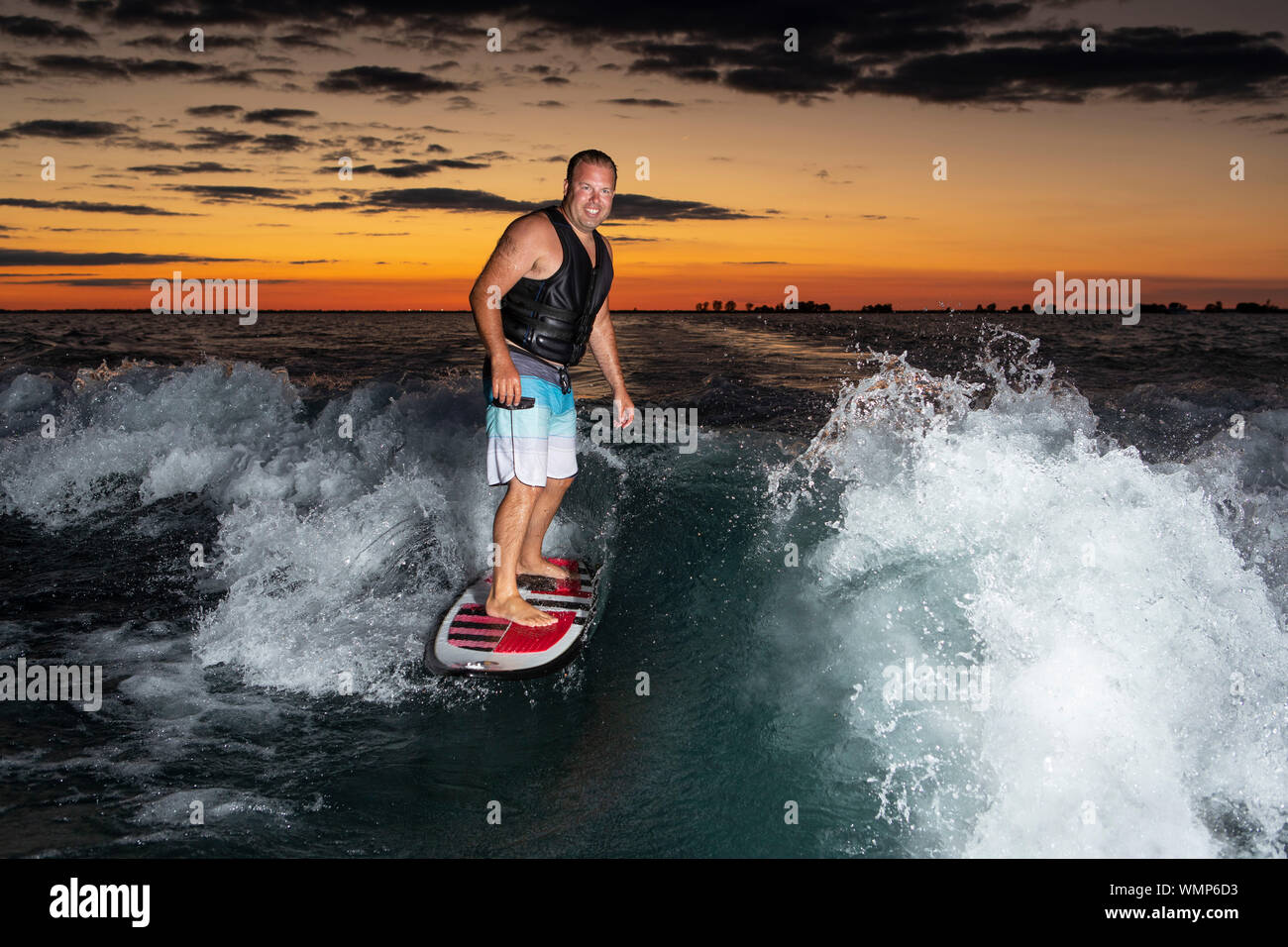 A Man Surfing On A Boat Wake Just After Sunset Stock Photo Alamy