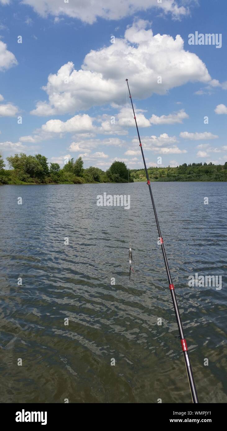 Fishing Rod By Lake Against Sky Stock Photo
