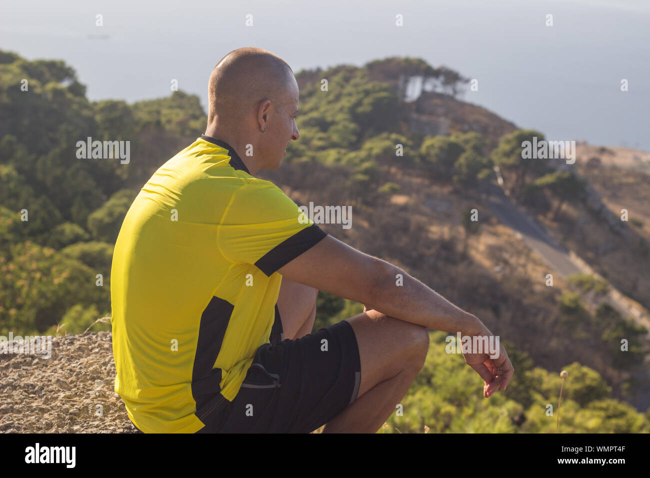 Man relaxing on mountain top after hiking workout Stock Photo