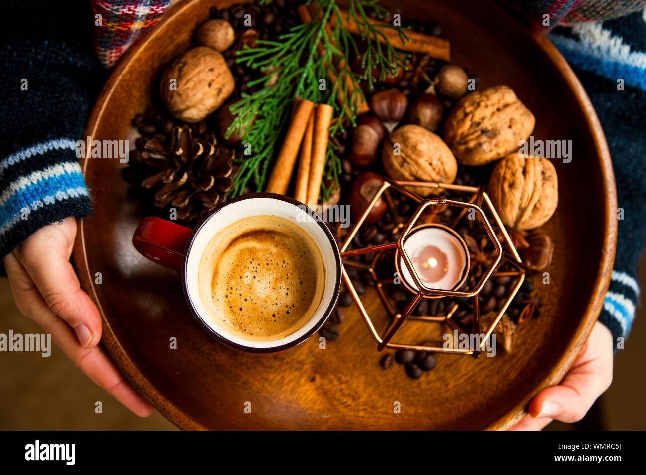 Rustic autumn wooden tray with coffee cup, candle, spices and nuts, autumn deco tray, woman holding wooden tray with fall deco and warm coffee, top vi Stock Photo