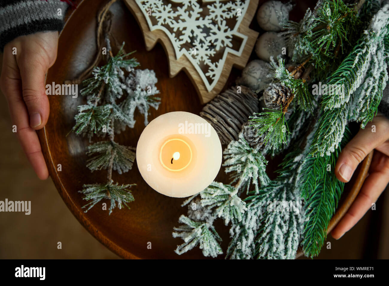 Fall /winter cozy home deco concept with woman holding wooden tray with fir tree branches and candle, cozy home concept Stock Photo