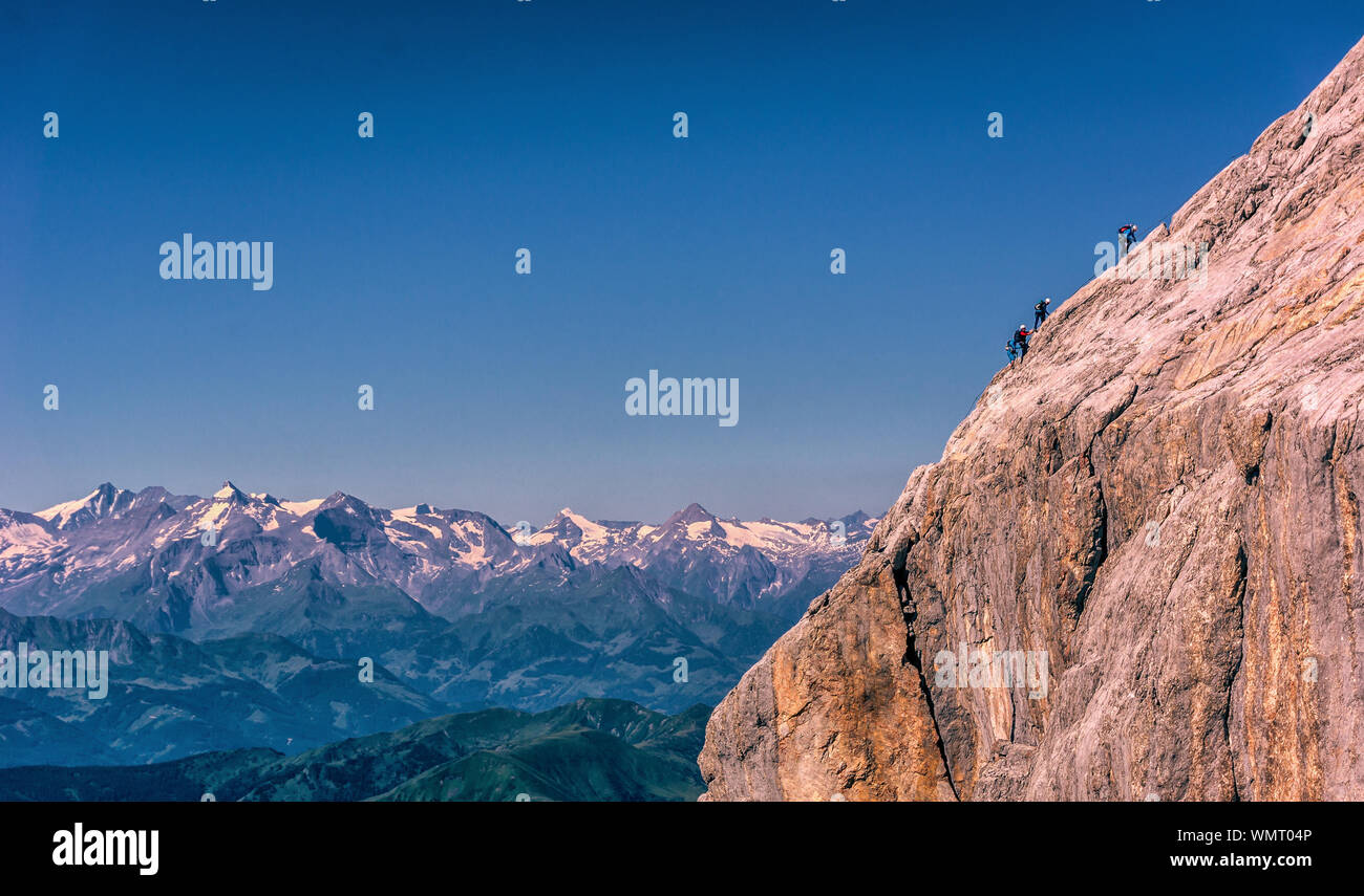 Four People Climbing Extreme Terrain In The European Alps Stock Photo