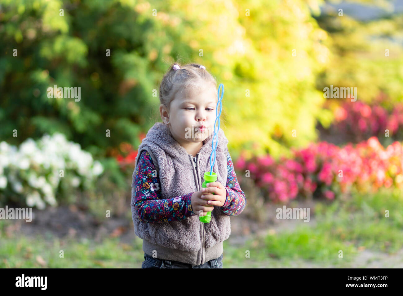Portrait of little girl blowing soap bubbles in park Stock Photo - Alamy