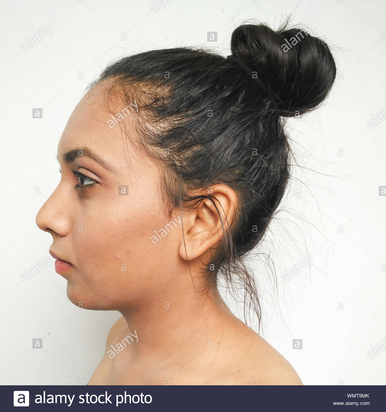 Side View Of Shirtless Woman With Hair Bun Against White